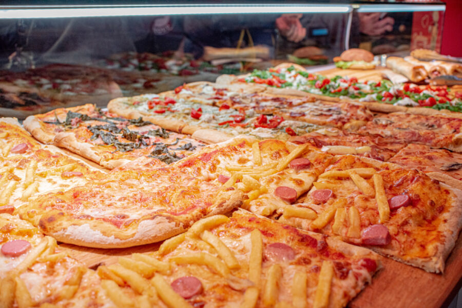 Display of pizza al taglio featuring various flavors, freshly baked and ready for sale