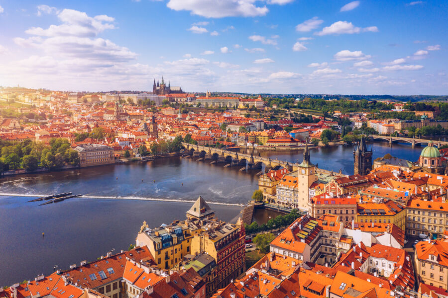 Scenic aerial view of Prague's Old Town, highlighting the Charles Bridge and Vltava River amidst springtime architecture