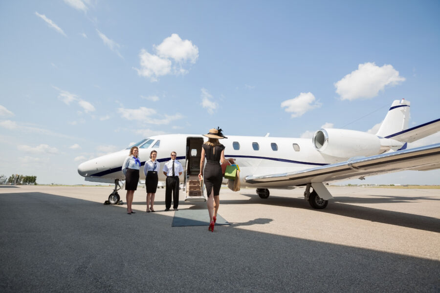 Woman confidently approaches a private jet at an airport terminal, ready for her journey