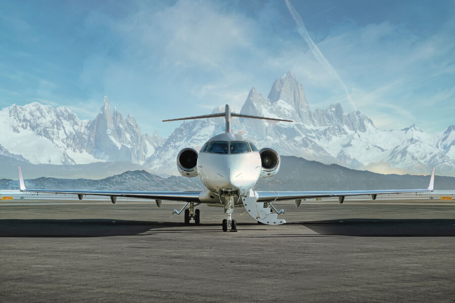 Private jet on the ground, ready for boarding, set against a backdrop of stunning snowy mountains