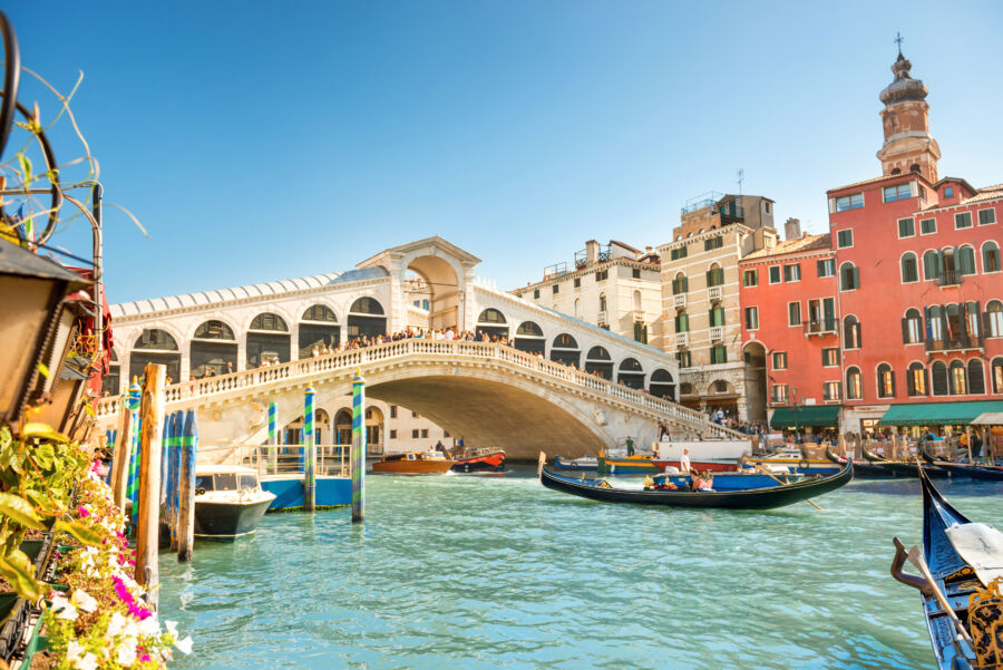 Panoramic view of the Rialto Bridge over the Grand Canal in Venice, highlighting its historic design and bustling atmosphere