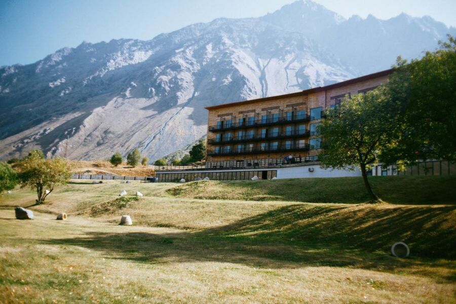 Exterior view of Rooms Hotel Kazbegi, showcasing its modern architecture against the backdrop of the Caucasus Mountains in Georgi