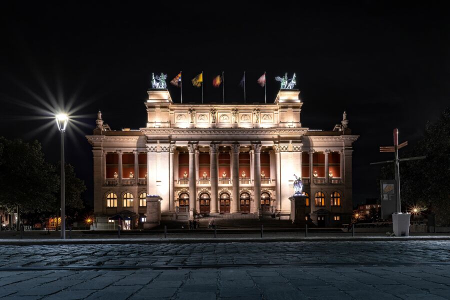 Night view of the Royal Museum of Fine Arts in Antwerp, Belgium, illuminated with various country flags displayed