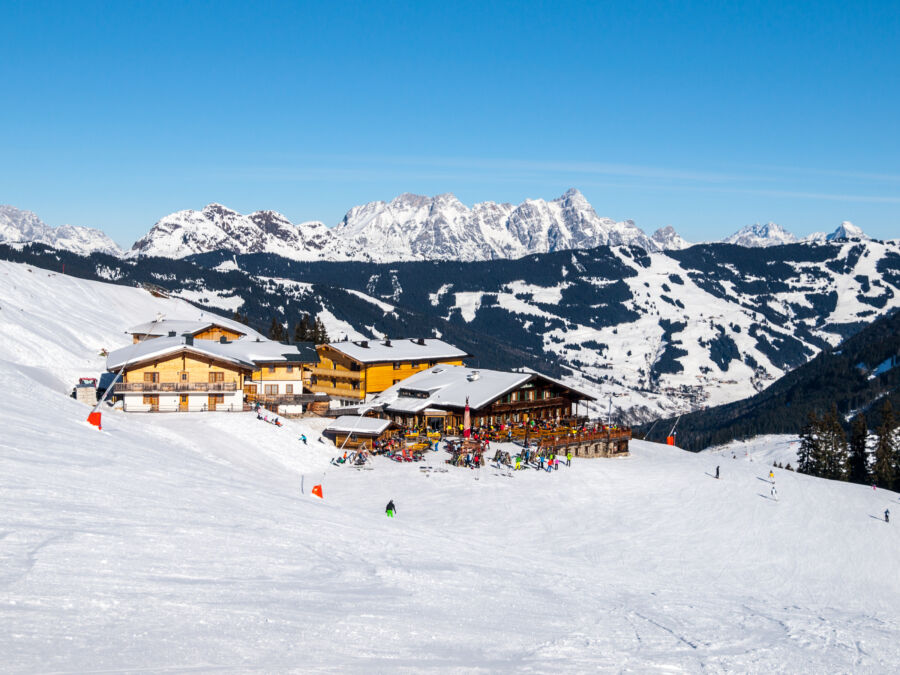 Winter scene of a downhill slope and a mountain hut with a restaurant terrace in Saalbach Hinterglemm, Tirol, Austria