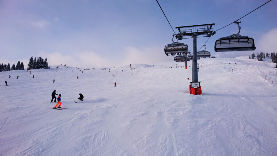 Skiers navigate the slopes of Saalbach-Hinterglemm, Austria, surrounded by snow-covered mountains and clear blue skies