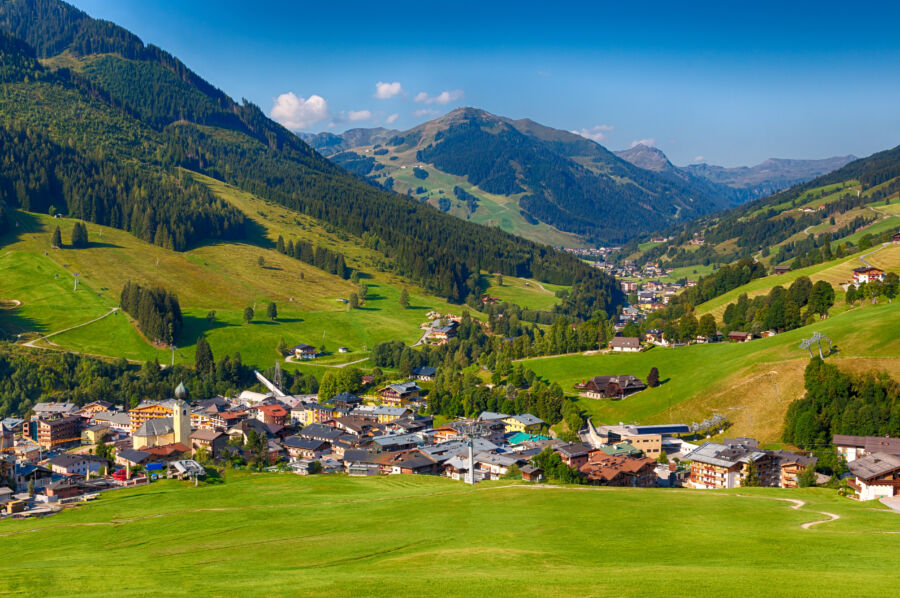 Panoramic view of Saalbach village in summer, showcasing lush green landscapes and the majestic Alps in the background