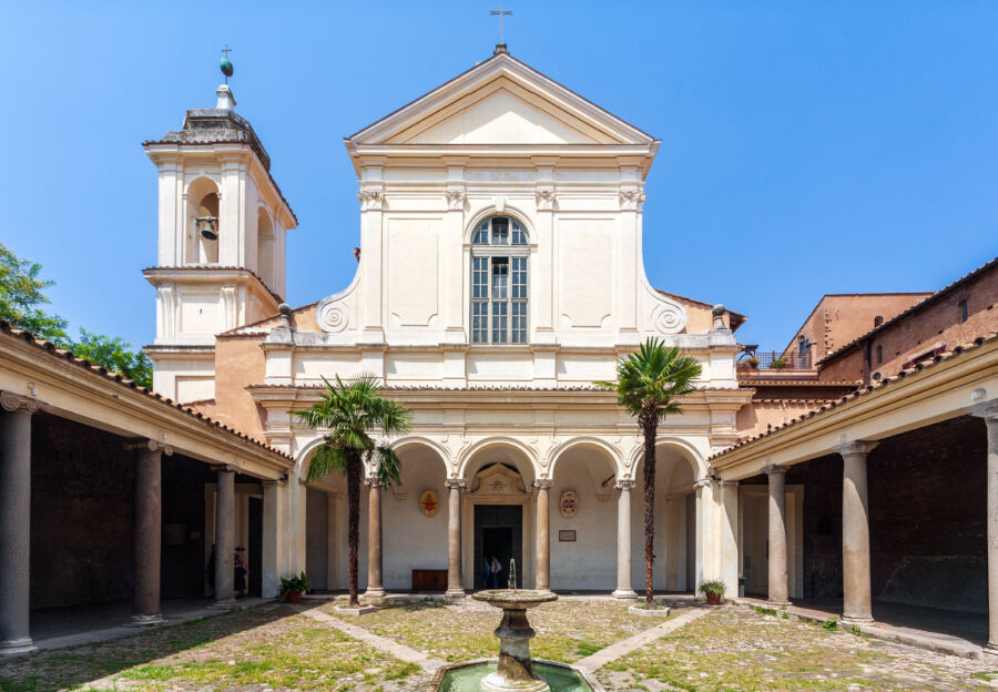 Serene courtyard of the Cloister of San Clemente Basilica in Rome, featuring elegant arches and lush greenery