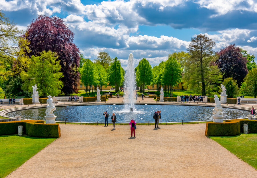 Springtime view of a fountain in Sanssouci Park, adorned with vibrant flowers, located in Potsdam, Germany