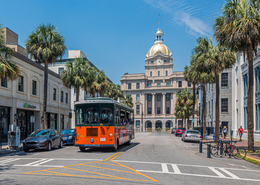 Tour bus parked in front of Savannah's City Hall, showcasing the building's historic architecture and vibrant surroundings