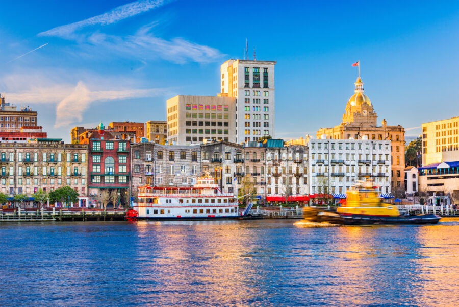 Cityscape of Savannah, Georgia, showcasing its skyline with historic buildings and lush greenery under a clear blue sky