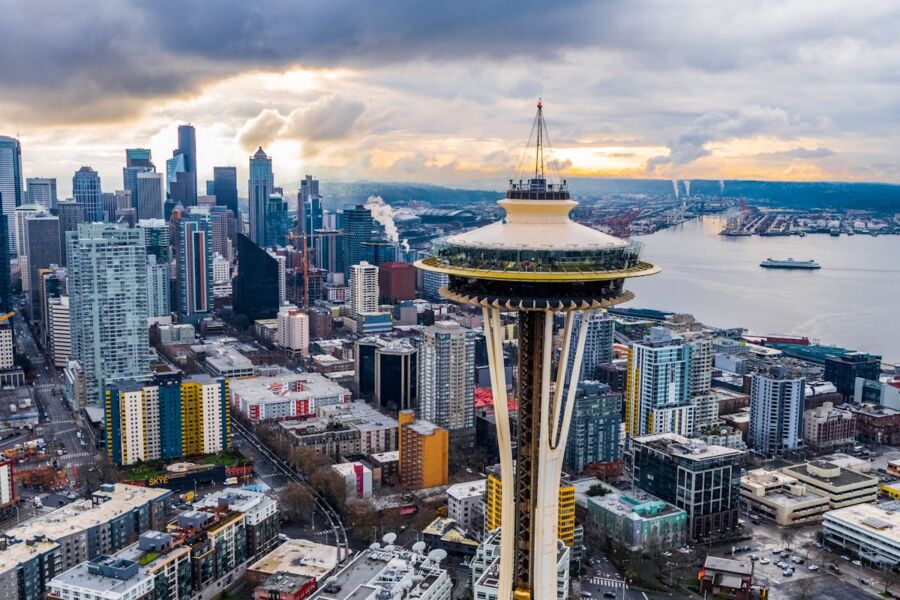 Seattle Space Needle with cityscape, sunset, and Puget Sound in the background.