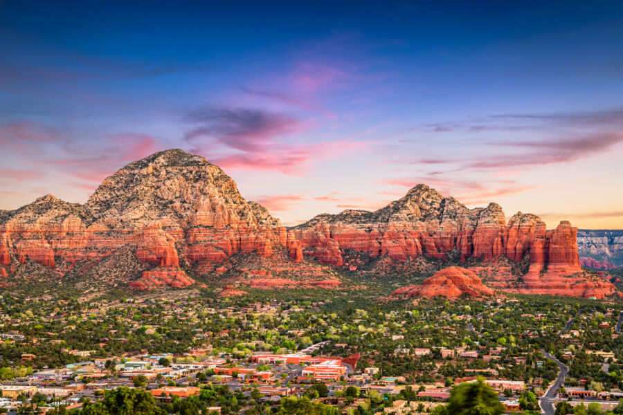 Vibrant sunset casts a warm glow over Sedona, Arizona, illuminating the stunning red rock skyline in the background