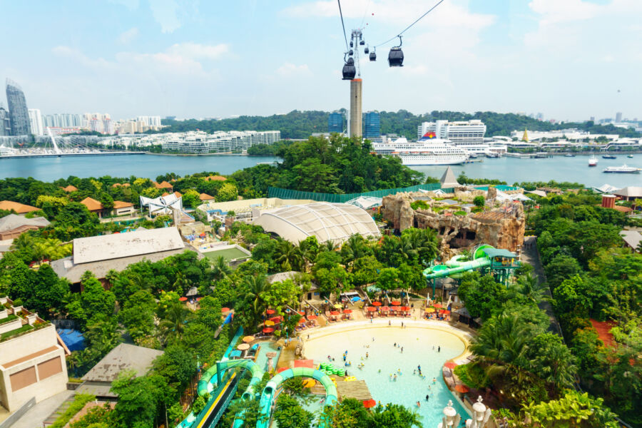 Aerial perspective of Sentosa Island, highlighting cable cars, verdant landscapes, beaches, and attractions in Singapore