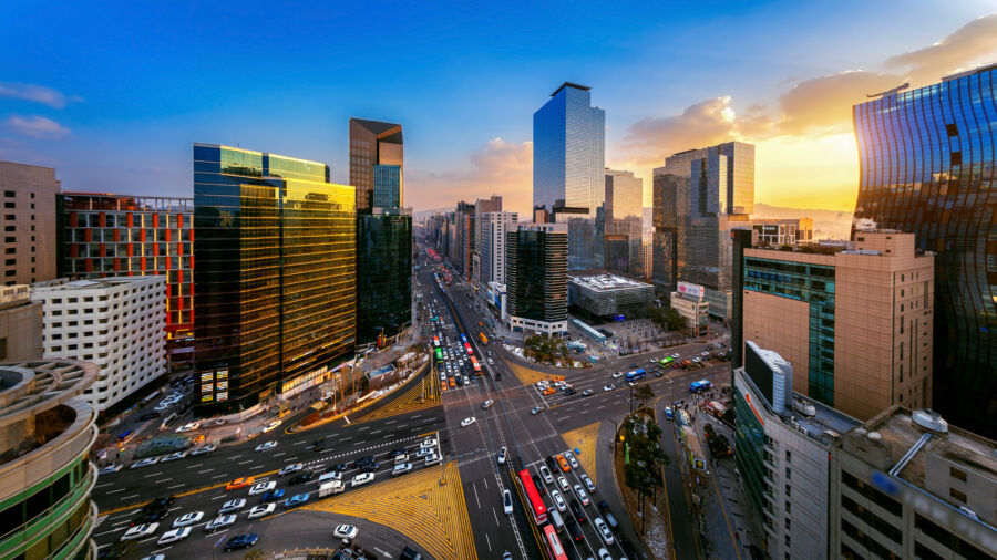 Sunset illuminates a busy intersection in Gangnam, Seoul, as vehicles navigate through the lively urban environment