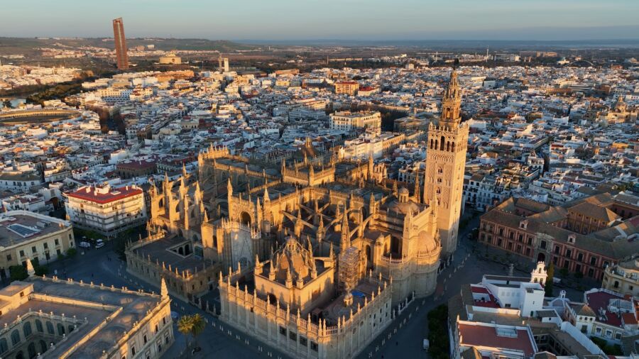 Aerial view of Seville at sunrise, showcasing the gothic cathedral and iconic Giralda bell tower in the city center