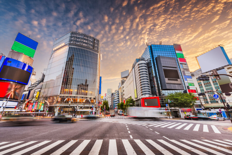 Panoramic view of Shibuya Crossing in Tokyo, Japan, bustling with pedestrian lanes and surrounded by tall buildings