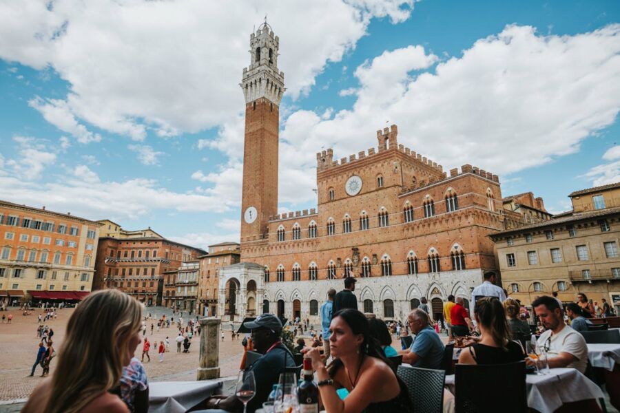 Piazza del Campo, Siena: Torre del Mangia, medieval architecture, dining, lively atmosphere.