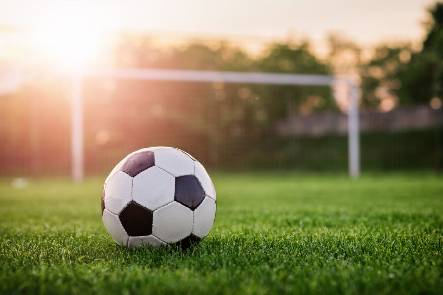 Close-up of a soccer ball on a lush football field, highlighting the essence of the game