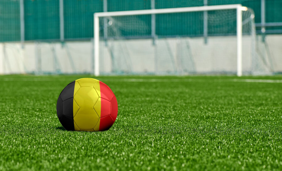 Soccer ball on a green field, featuring the flag of Belgium prominently in the scene