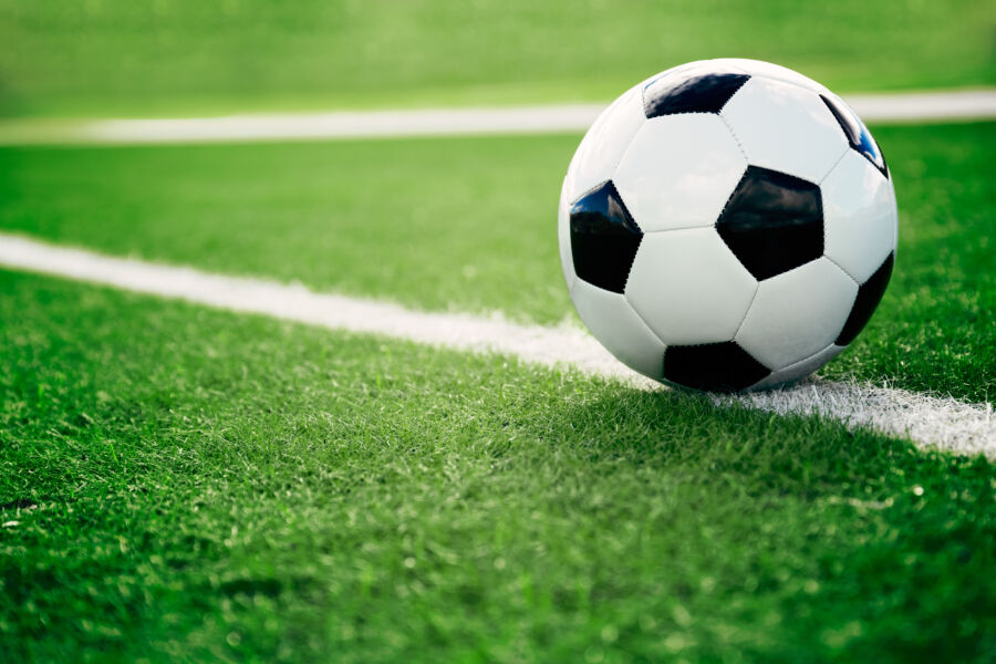 Close-up of a soccer ball resting on a vibrant green soccer field, showcasing its texture and design