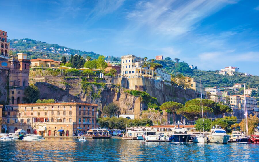 Panoramic view of Sorrento's coastline featuring luxury hotels along the shore and the sea in the background