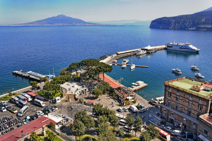 Port of Sorrento, Italy, featuring boats docked along the waterfront with scenic views of the surrounding landscape