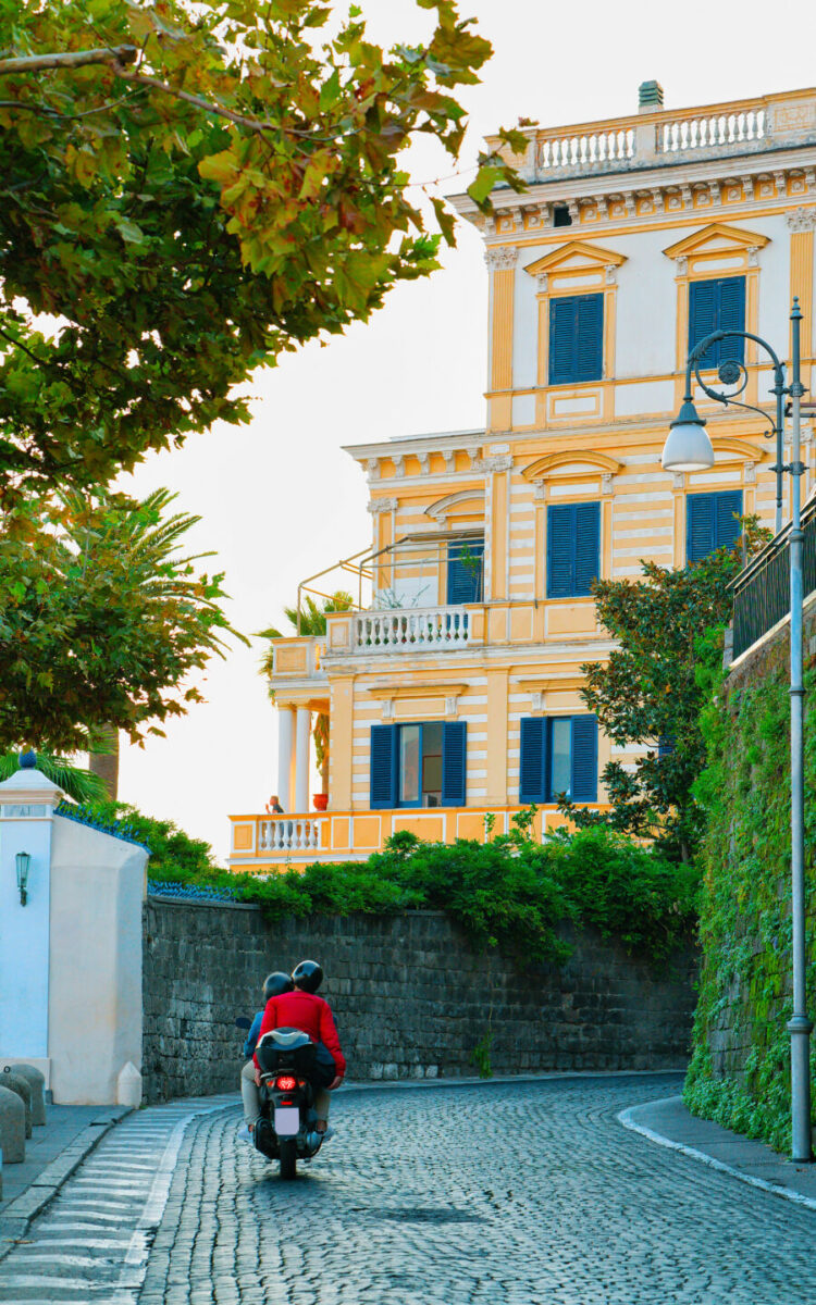 Tourists riding a motorcycle through the historic streets of Sorrento, reflecting the vibrant atmosphere of the area