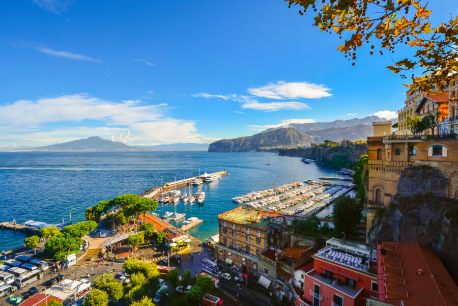 Scenic view of Sorrento, Italy, showcasing the bay, marina, and colorful town against the backdrop of Mt. Vesuvius