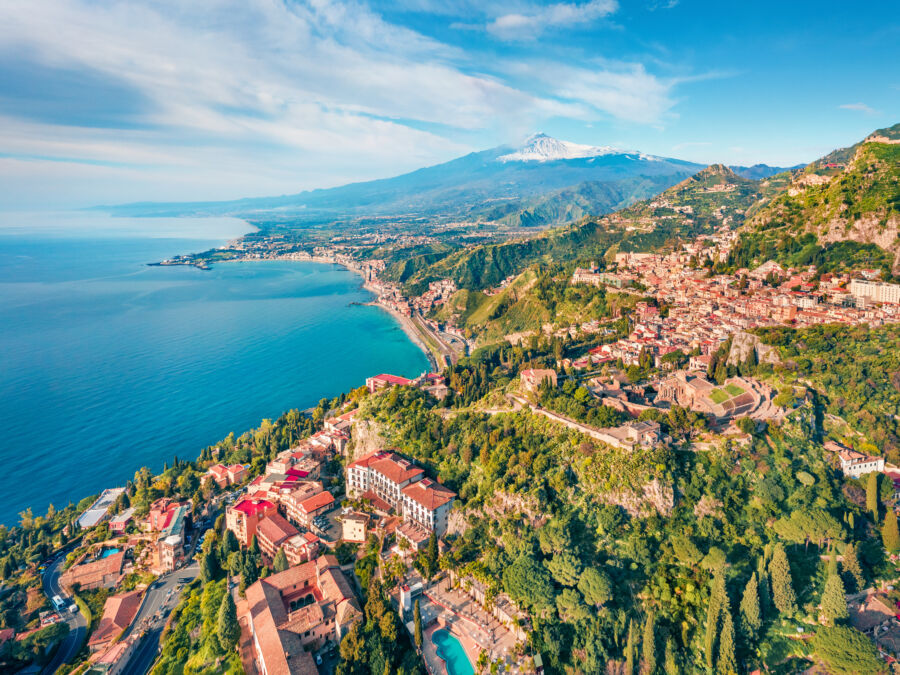 Aerial view of Taormina, Italy, captured by a drone on a sunny morning, showcasing the town's picturesque landscape