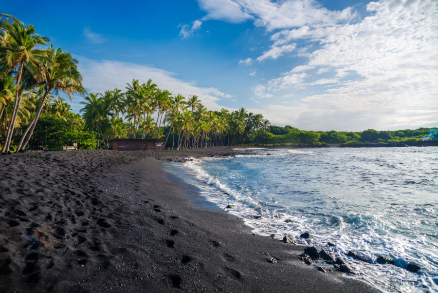 Panoramic view of Punaluu black sand beach on the Big Island of Hawaii, showcasing the unique shoreline and vibrant skyline.