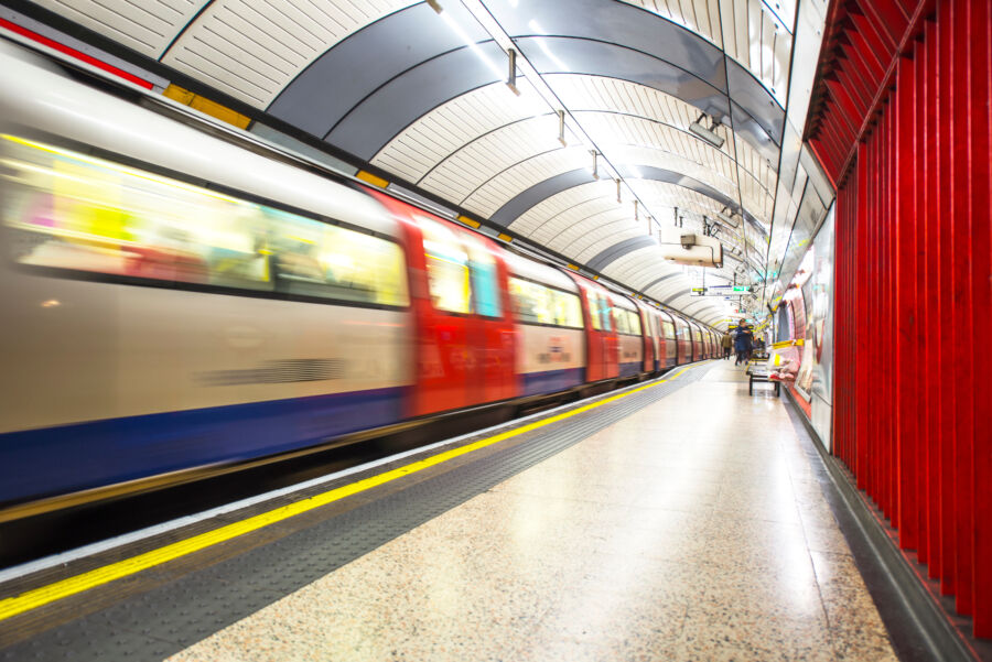 Fast-moving tube train rushes by a London station, highlighting the efficiency of the city's underground transit