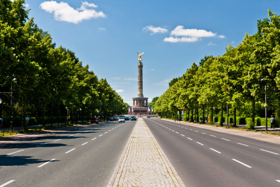 The Victory Column in Tiergarten, Berlin, framed by lush trees, representing a historic landmark in a green setting