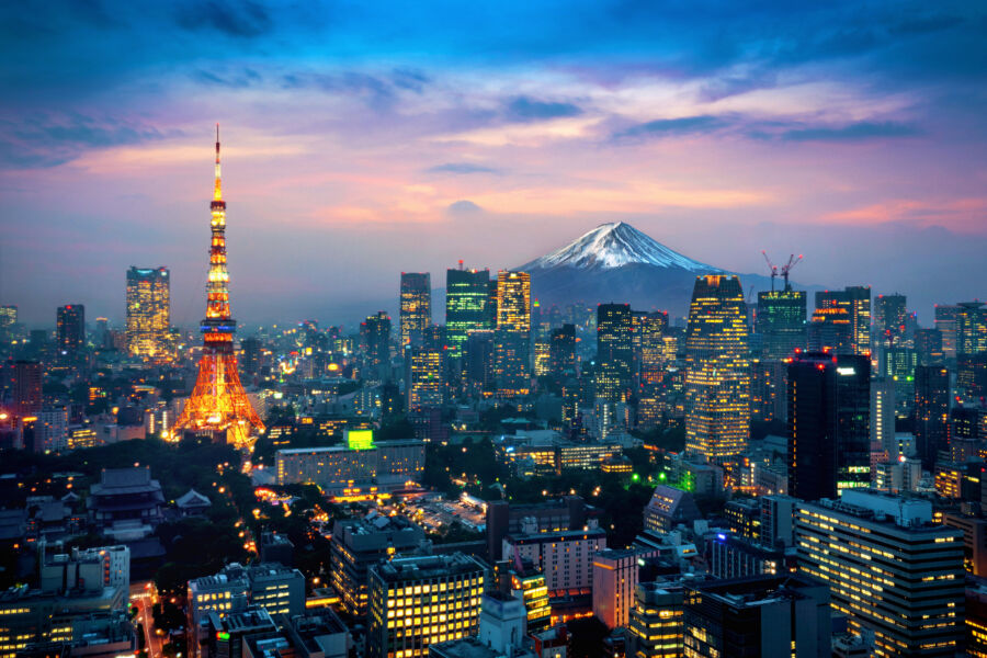 Nighttime aerial view of Tokyo, showcasing the city lights and the majestic Mount Fuji in the distance