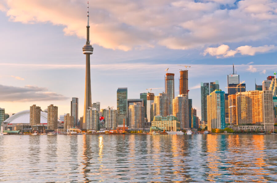 Reflection of Toronto skyline at dusk, showcasing vibrant city lights and serene water in Ontario, Canada