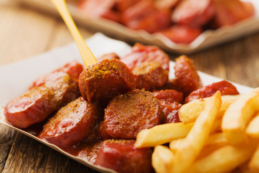 Traditional German currywurst paired with crispy chips, elegantly arranged on a disposable plate for a convenient meal