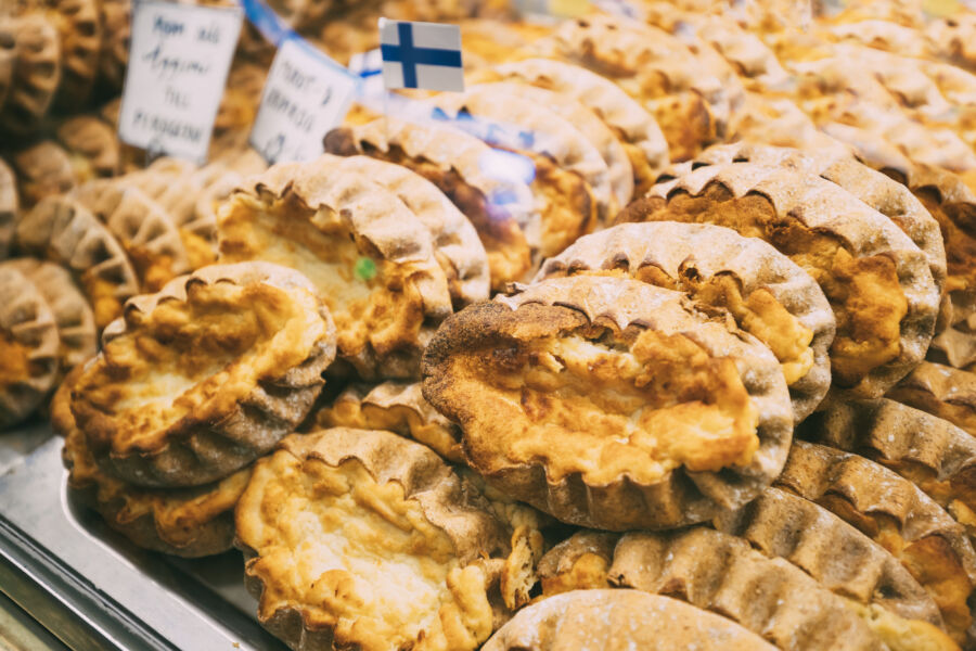 Traditional Finnish Karelian pasties Karjalanpiirakka displayed with a Finnish flag