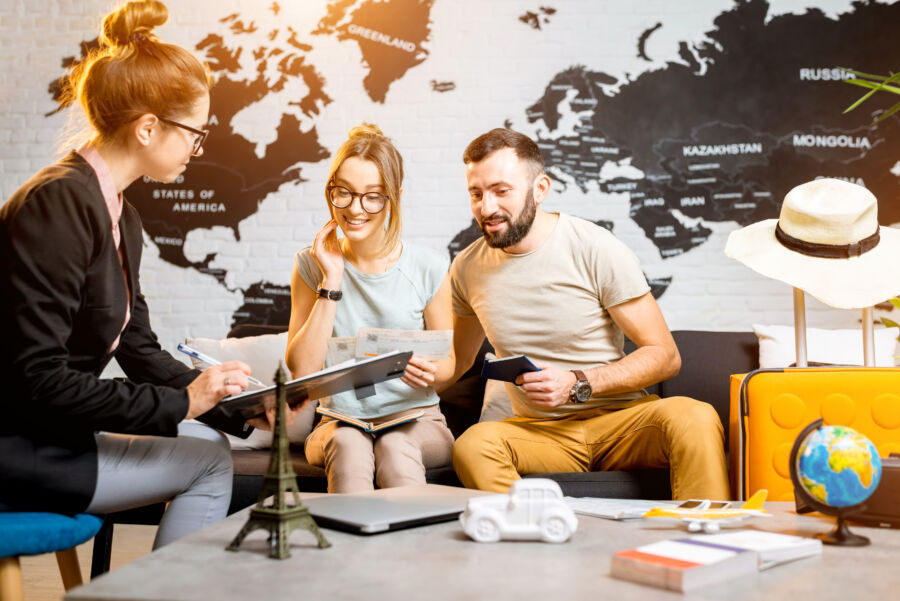 Lovely young couple discusses summer vacation plans with a travel agent