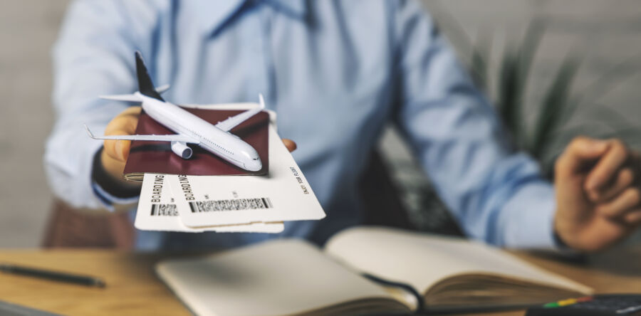 Inside a travel agency, an agent displays flight tickets and a plane model, highlighting tourism services offered