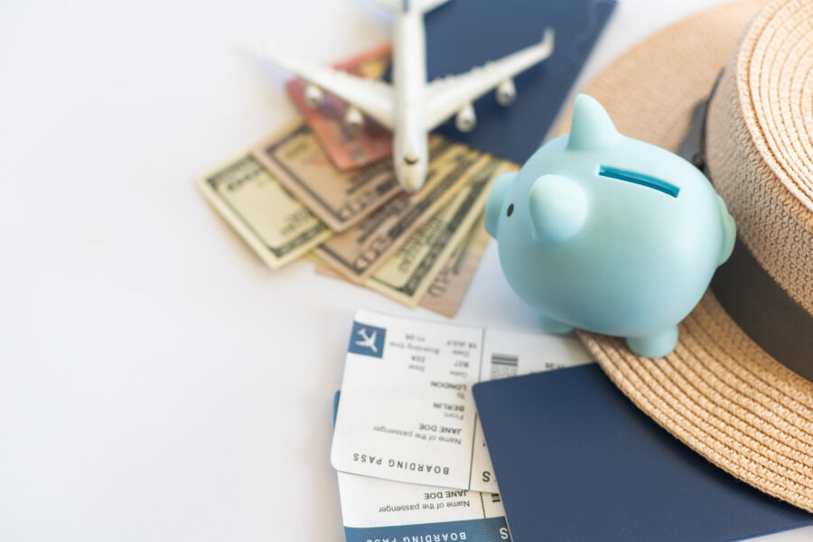 Airplane model beside a piggy bank on a wooden table, symbolizing travel budgeting and money-saving strategies