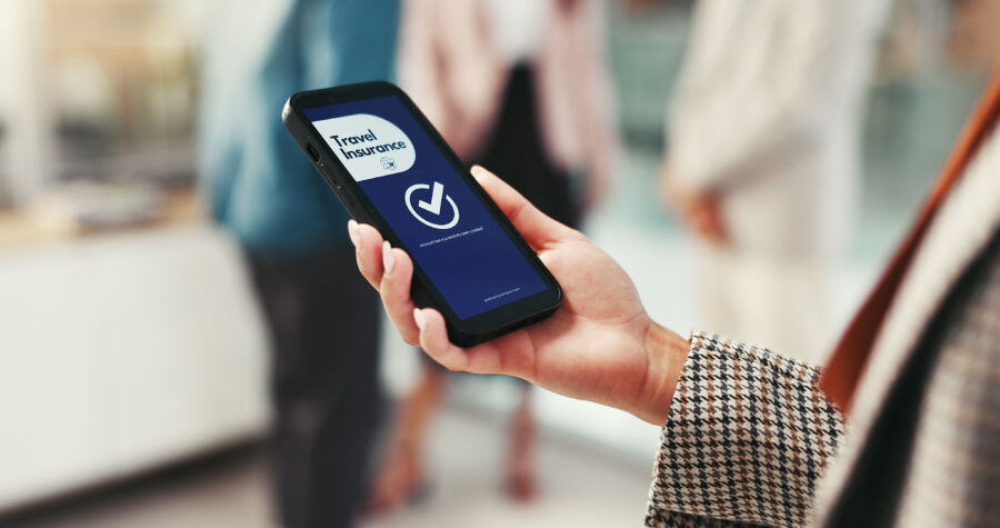 Close-up of a woman's hands on a phone showing a travel insurance website, highlighting travel safety and support