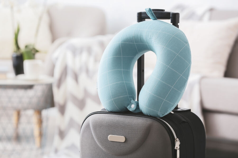 Close-up of a travel pillow rests on a suitcase in a cozy room