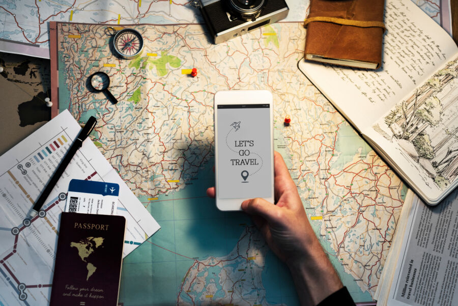 Close-up of a hand holding a mobile phone, set against a background of a travel map, illustrating a travel plan and itinerary