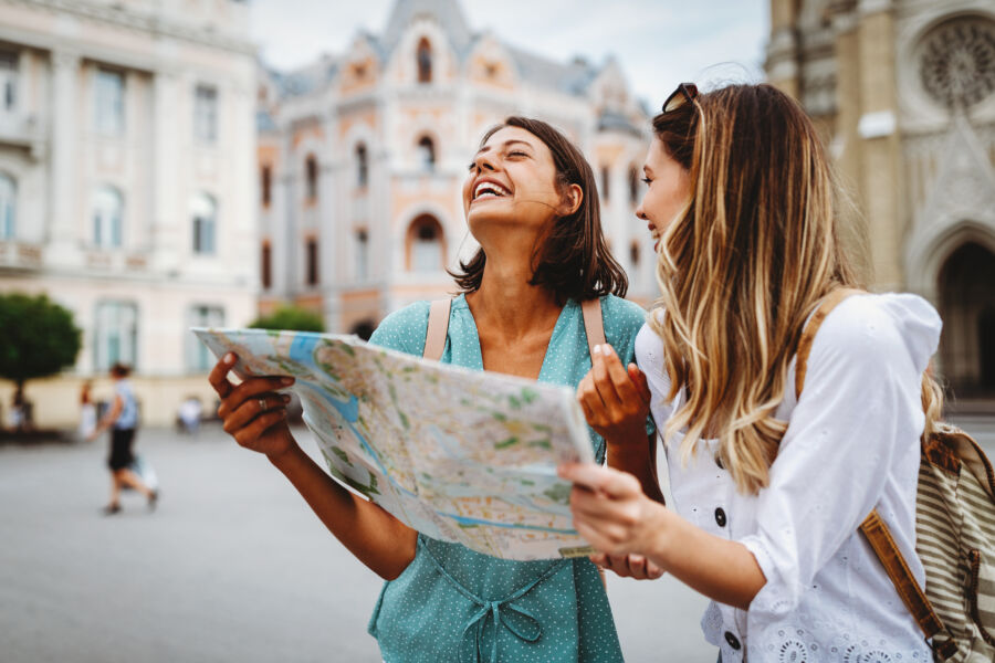 Two female travelers consult a map while exploring the city, seeking directions to their next destination