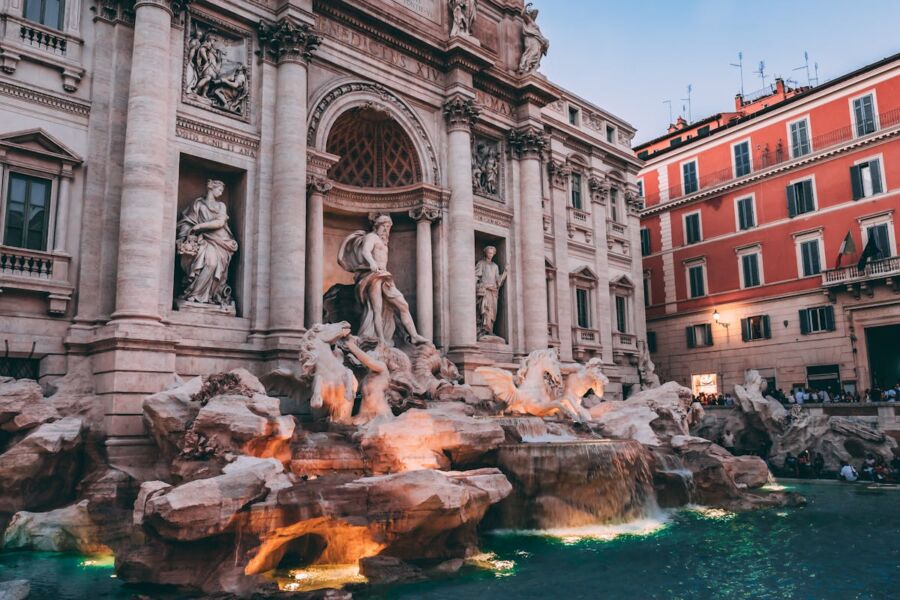 Twilight view of Romes iconic Trevi Fountain with sculptures and visitors.