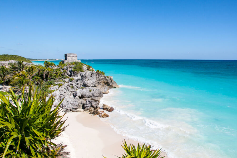 Scenic panorama of Tulum Beach featuring the Temple of the Wind God, with vibrant ocean hues and lush greenery surrounding it