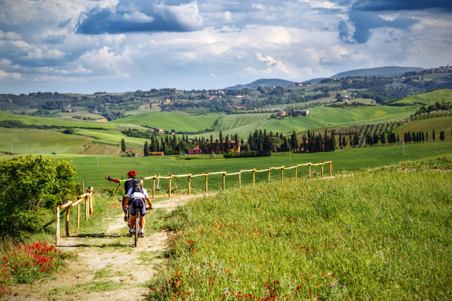 Mountain bikers navigating a scenic trail through the picturesque landscapes of Tuscany