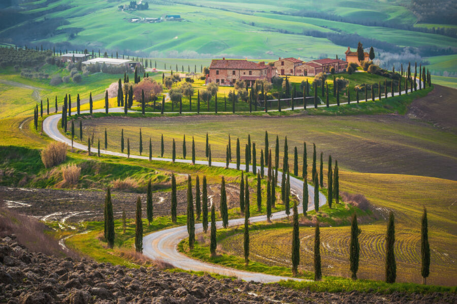 Aerial view of sunlit fields in Tuscany, Italy, showcasing vibrant green and golden landscapes