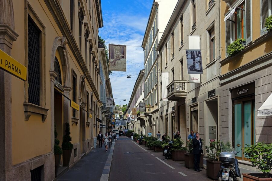 Elegant urban street scene with historic architecture, luxury shops, and stylish pedestrians.