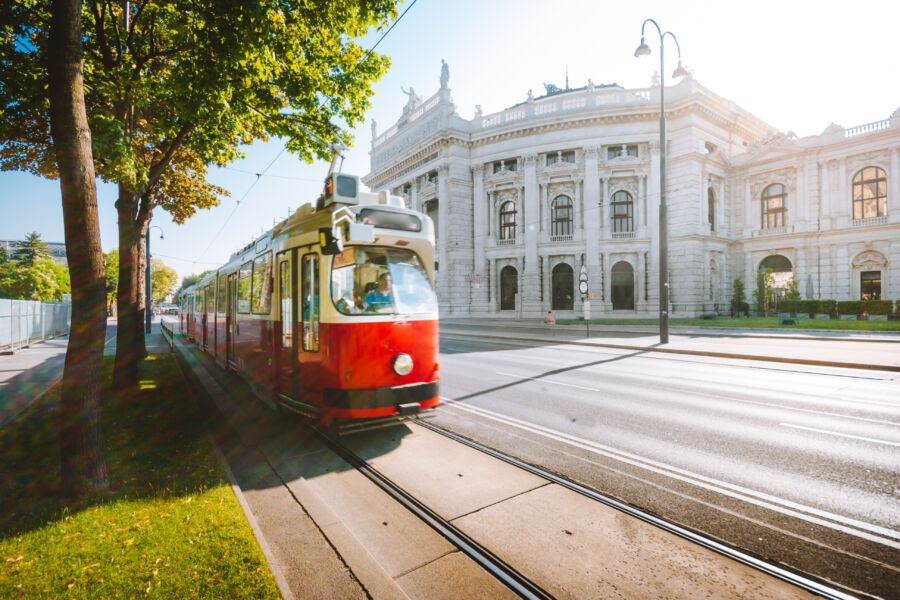 Vienna tram passing by Burgtheater at sunrise, casting a warm glow over the historic architecture in Austria