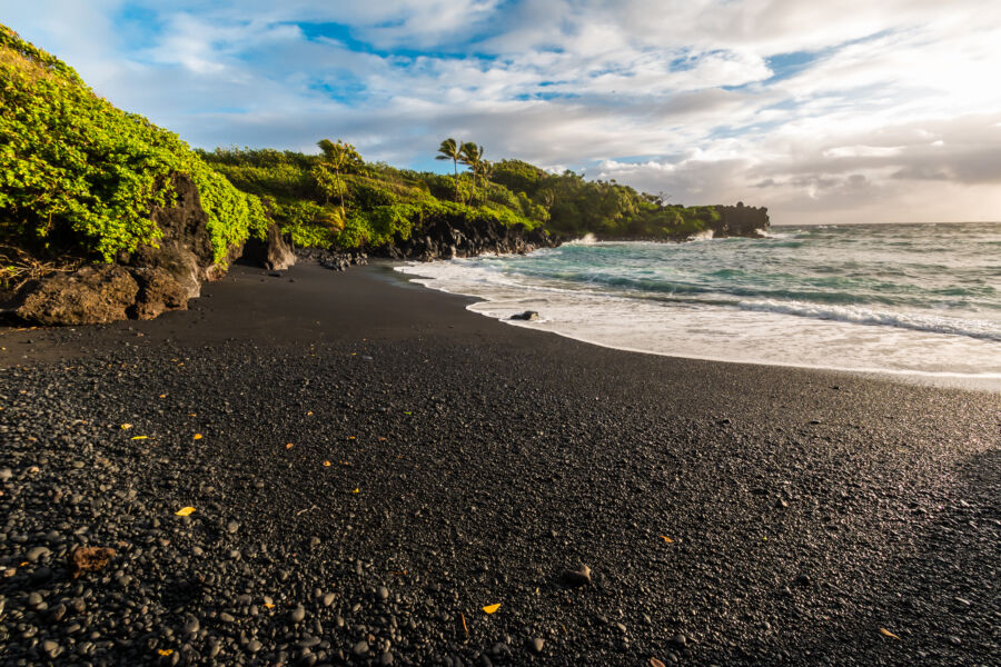 Pa'iloa Black Sand Beach at Wai'anapanapa State Park, Maui, features striking black sand and stunning coastal scenery.